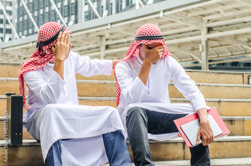 Two upset arab businessman sitting at stairs in the modern city, feeling down, disappointed from business problem concept