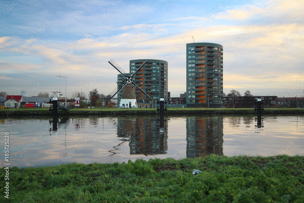 Windmill is reflecting on the water of canal Gouwe in Gouda