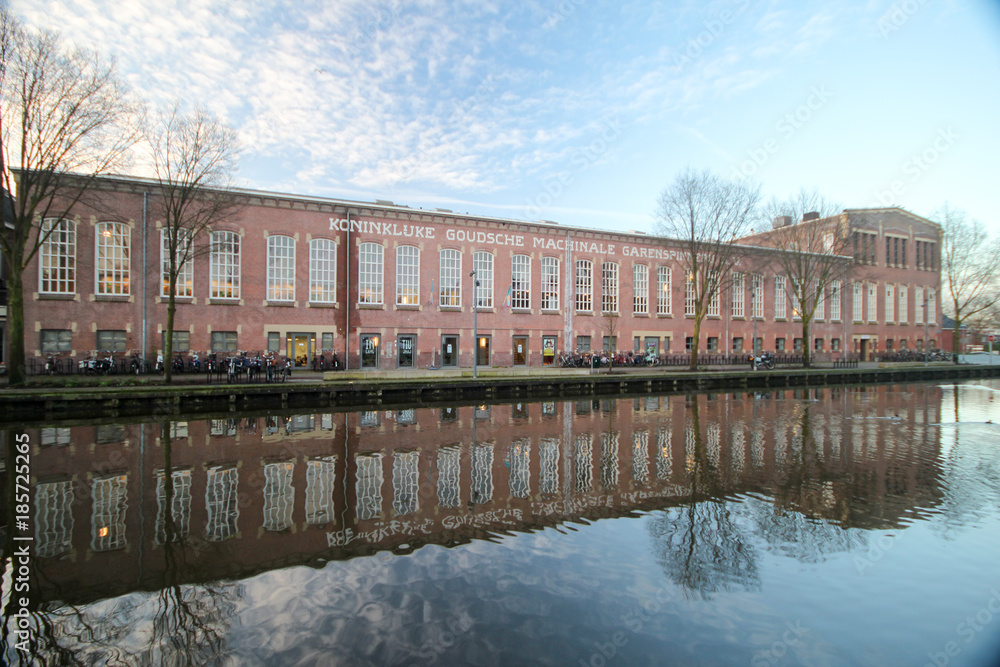 Restaurated factory named garenspinnerij mirrors in canal water in Gouda, Netherlands