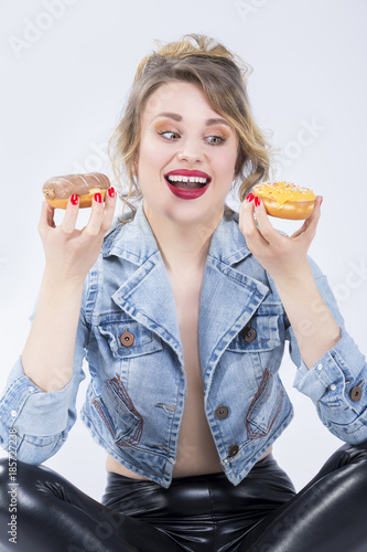 Food Ideas and Concepts. Young Caucasian Blond Girl Playing With Doughnut in Hands. Posing Against White.