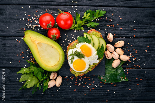 Avocado sandwich with quail eggs, cucumber and pistachios. On a wooden background. Top view. Free space for your text.