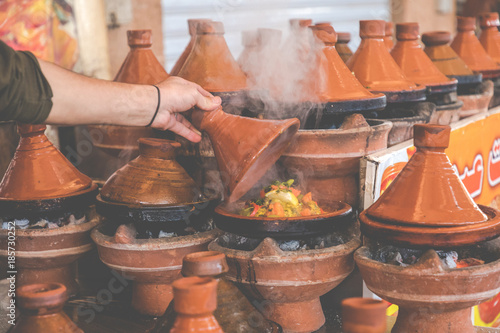 Preparing food in tajin traditional dish in Morocco - meat and vegetable in a ceramic tajine.