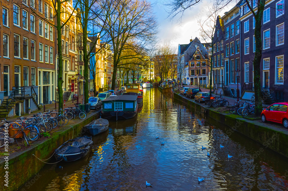 The most famous canals and embankments of Amsterdam city during sunset.