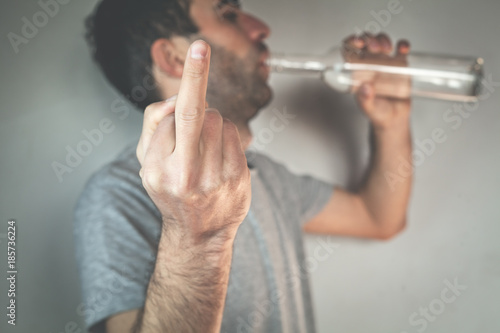 фотографія Caucasian man drinks vodka and showing fuck you sign.