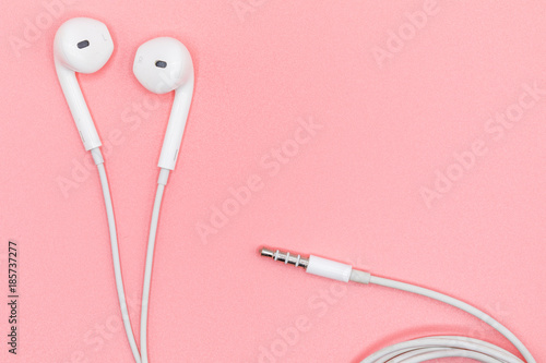 Top view Lovely Closeup of White Earphones on Pink Pastel plastic texture background. Pastel color concept, Minimal concept. Copy space. Music is my life concept. Valentine concept