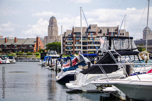 Exterior daytime stock photo of boats resting in Erie Basin Marina in foreground and apartments and Buffalo City Hall in background in Buffalo New York Erie County