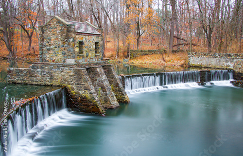 Exterior daytime long exposure stock photo of stone structure on dam and waterfall on Speedwell Lake in Morristown New Jersey in Morris County on overcast fall day