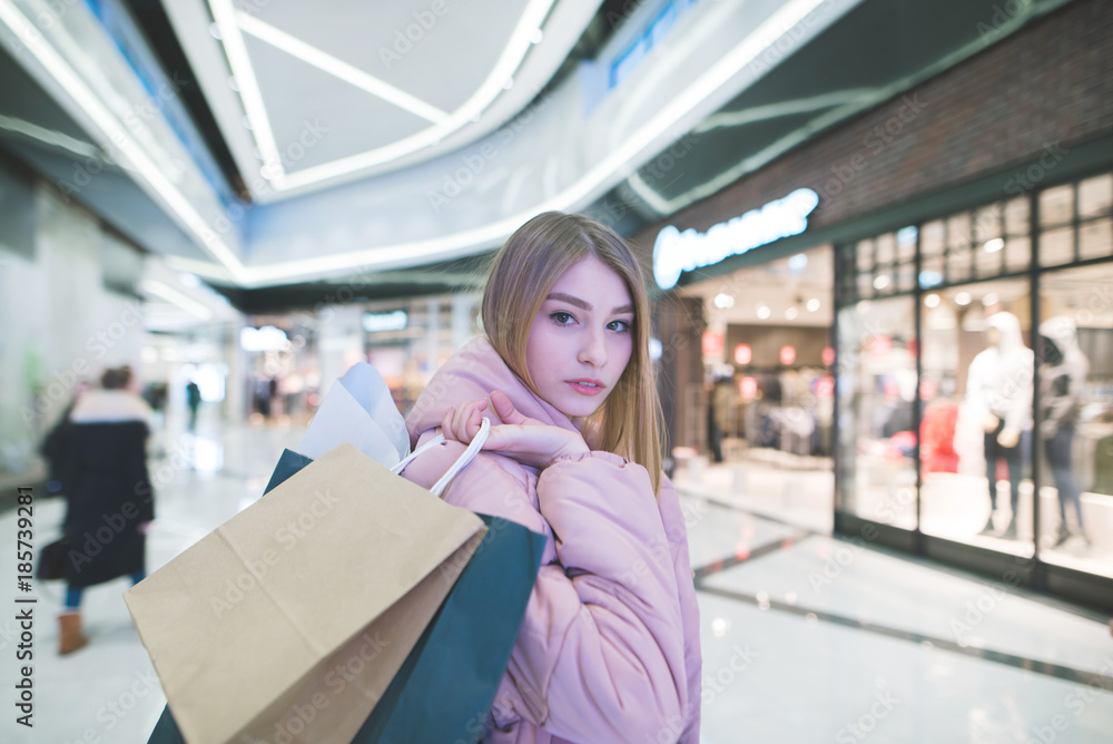 A sweet blonde with shopping bags in the hands of a mall looking into the camera. Shopping concept. A sweet blonde with shopping bags in the hands of a mall looking into the camera. Shopping concept.