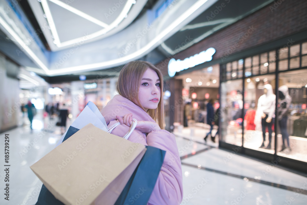 A sweet blonde with shopping bags in the yoke goes to the mall and looks to the side. Shopping concept. A sweet blonde with shopping bags in the yoke goes to the mall and looks to the side. Shopping concept.