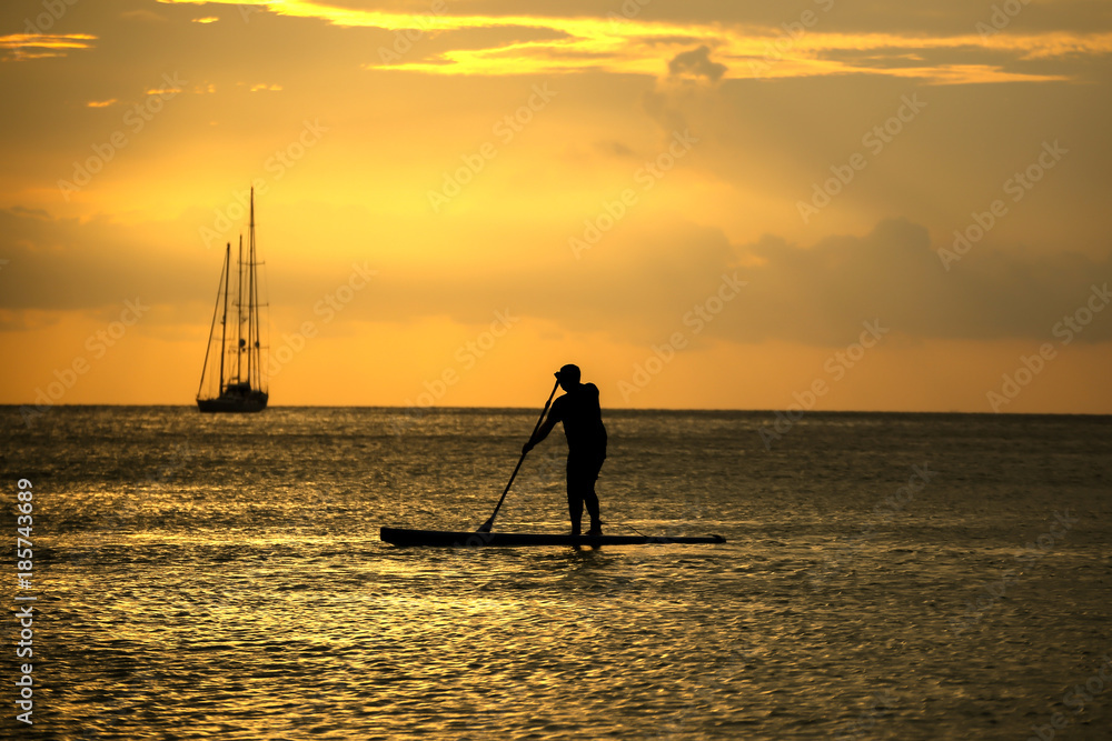 Silhouette of man with paddle and surf board sunset moment