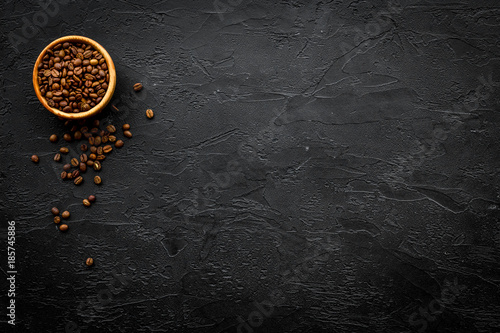 Coffee background. Roasted beans in bowl on black table top view copyspace
