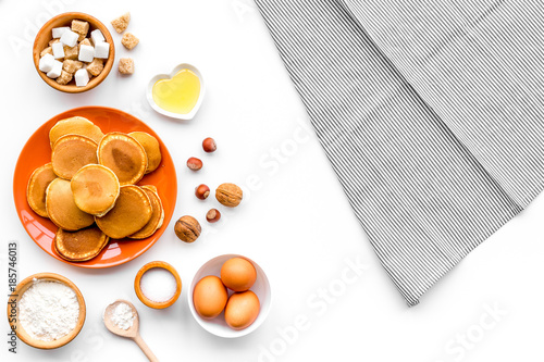 Cooking american pancakes. Ingredients, cakes, nuts and honey on white background top view mockup photo