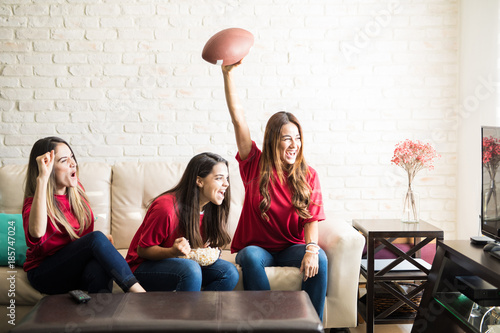 Tableau sur toile Women and football fans watching a game and celebrating