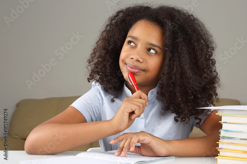 black schoolgirl is thinking about school homework doing homework.