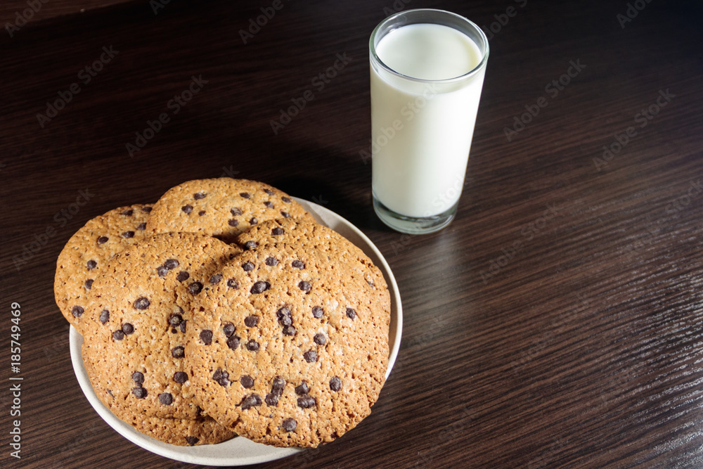 Chocolate chip cookies and glass of milk on wooden table Chocolate chip cookies and glass of milk on wooden table