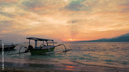 Beautiful morning sunrise on sandy beach with traditional Jakung canoe and dramatic sky on July 3, 2017 in Indonesia photo