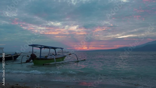 Traditional Jakung outboard canoe on beautiful beach front during morning sunrise with dramatic sky on July 3, 2017 in Indonesia photo