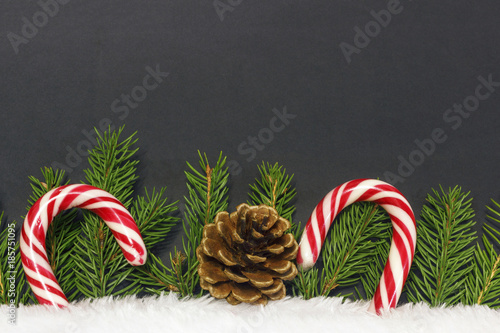  two sweets among the branches of a Christmas tree and white fur with a cone