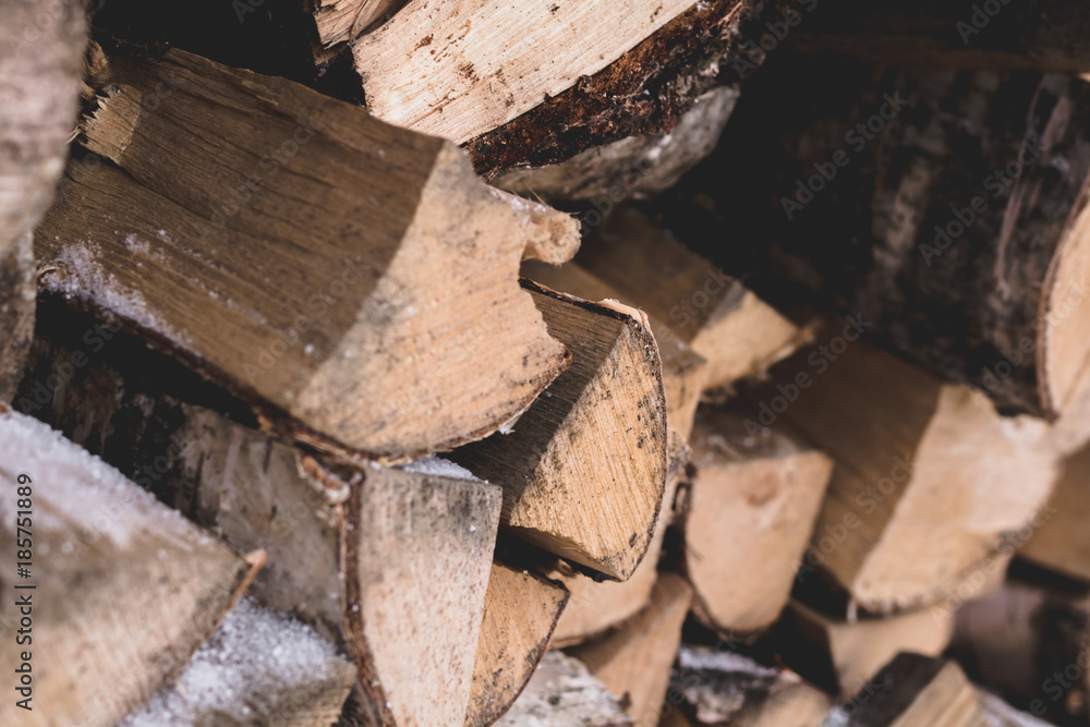 Firewood for kindling the fireplace are lying outdoor in the winter