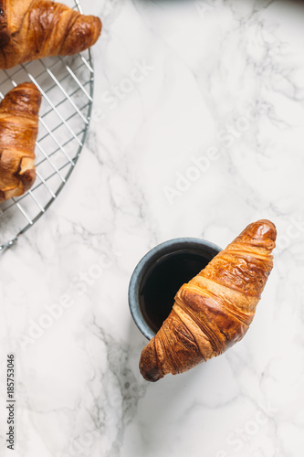 Cup of coffee and croissants on marble background