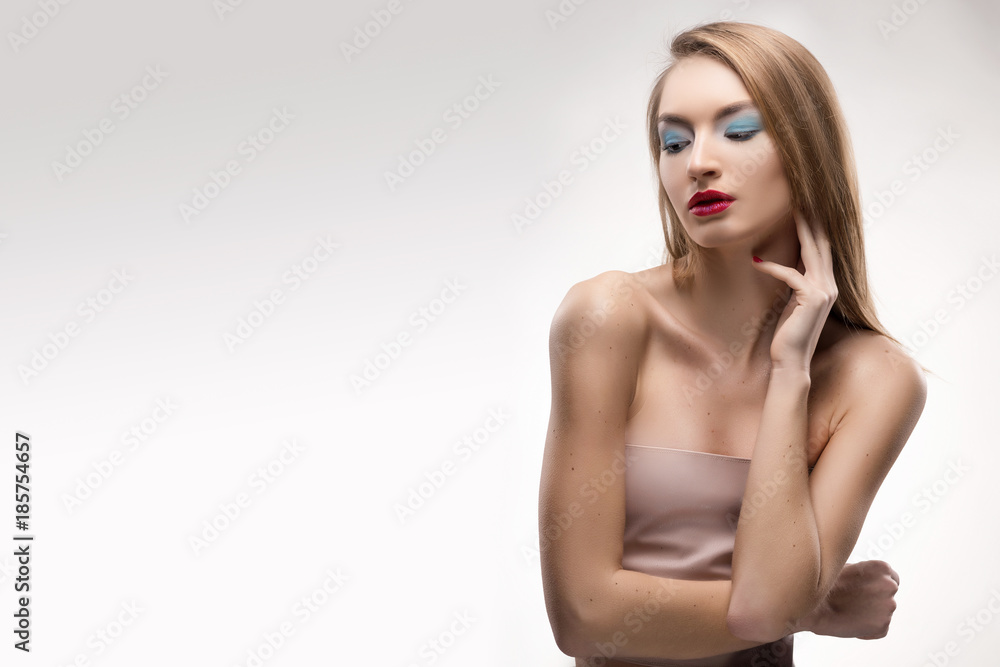 Obraz premium The beautiful blonde red lips smiling girl touches by fingers face and a neck and looks sideways
