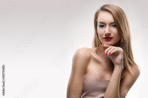 The beautiful blonde red lips smiling girl touches by fingers face and a neck