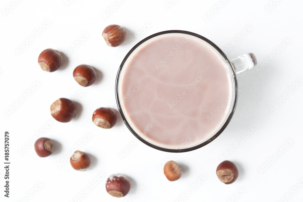 Winter drink. Warm cocoa with milk and hazelnuts on a white background. Flat lay. Morning light Winter drink. Warm cocoa with milk and hazelnuts on a white background. Flat lay. Morning light