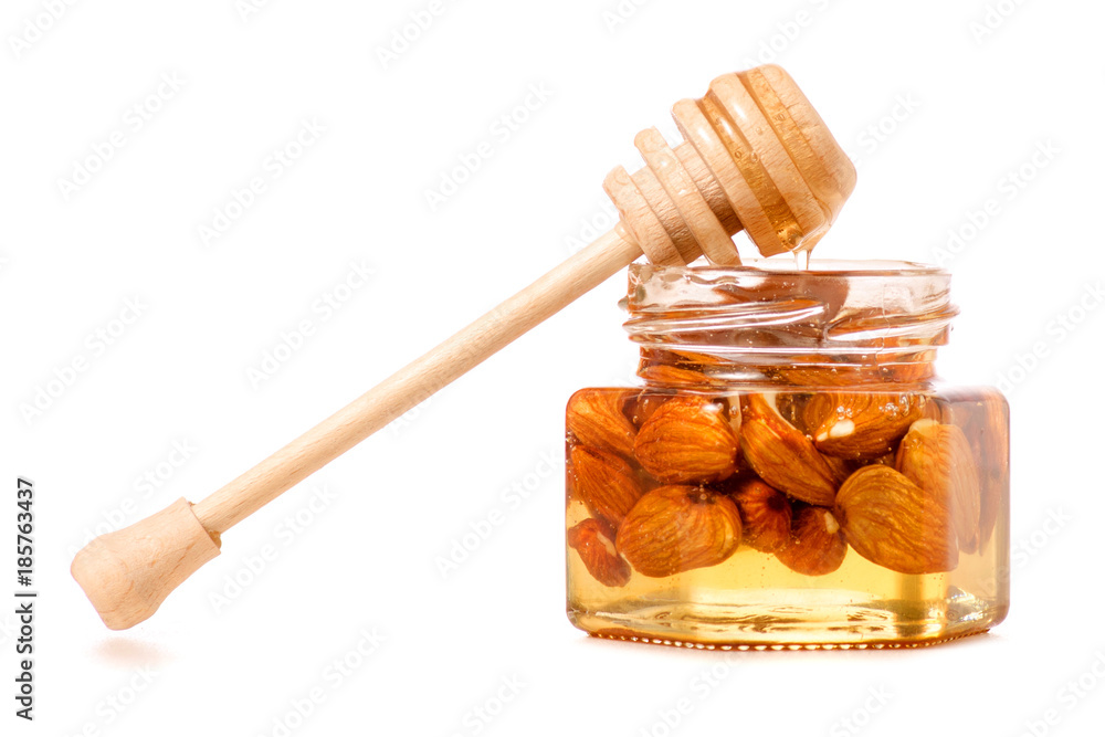 A honey jar with a spoon for honey nuts almonds A honey jar with a spoon for honey nuts almonds