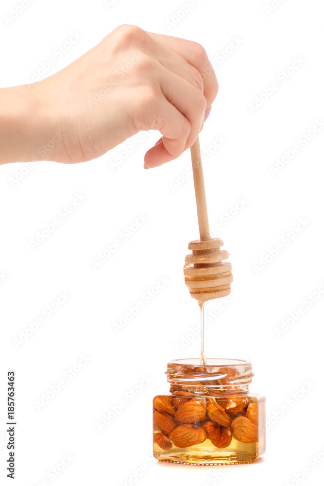 A honey jar with a spoon for honey nuts almonds in hands A honey jar with a spoon for honey nuts almonds in hands