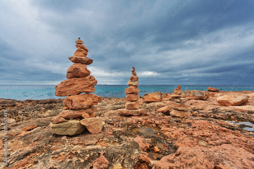 Stones stacks at rocks beach under gloomy sky