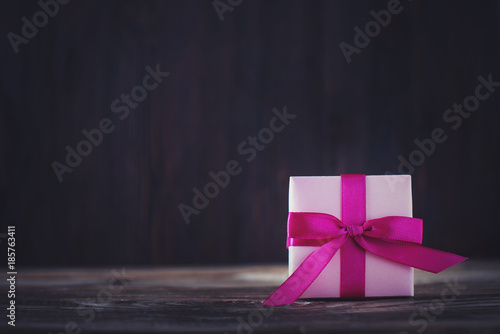 Box of gift with pink ribbon on dark wooden background, valentines and birthday theme