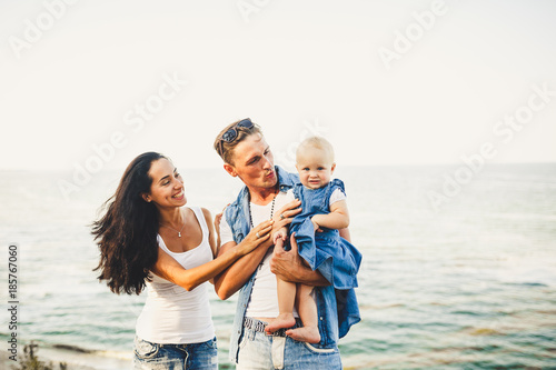 beautiful young family on vacation with baby. The father holds the blonde girl in her arms, and the brunette's mother hugs her husband. The concept of a family beach holiday summer near the sea