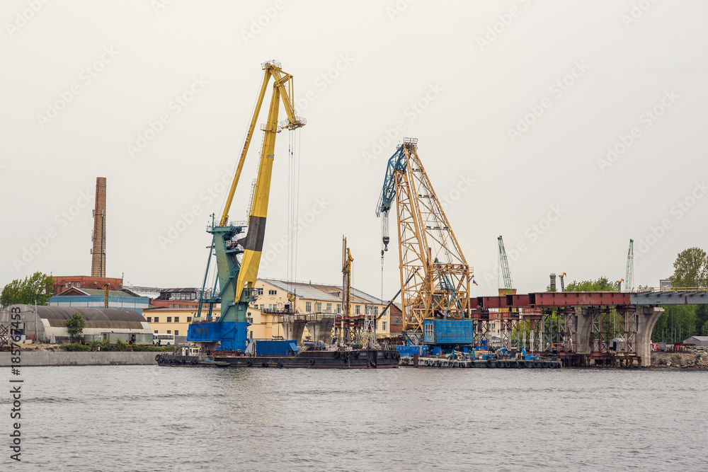 Cargo ship loading cranes in industrial zone on river, freight logistic transportation by water concept