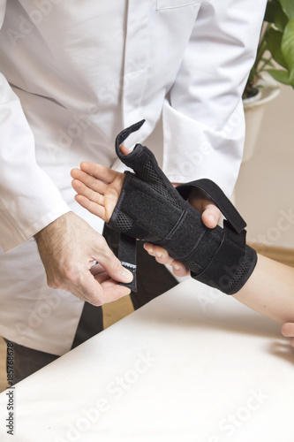 Lekarz ortopeda zakłada stabilizator na dłoń kobiety.