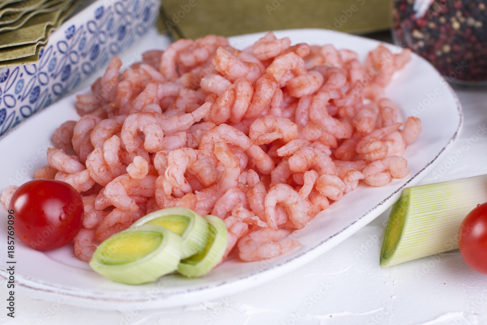 small shrimps on a plate and on lasagna sheets cherry tomatoes, on a white concrete background small shrimps on a plate and on lasagna sheets cherry tomatoes, on a white concrete background