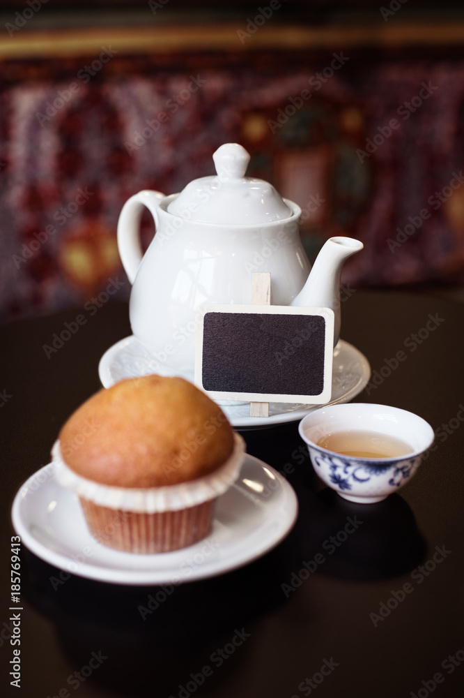 Kitchen tea time composition: white porcelan teapot, a cup with green tea and a muffin Kitchen tea time composition: white porcelan teapot, a cup with green tea and a muffin