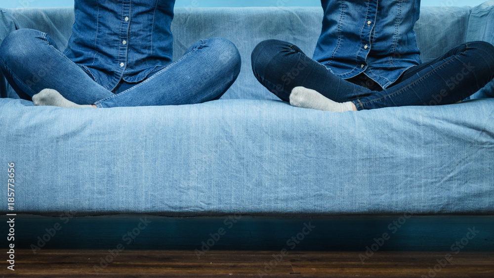 Two women wearing jeans sitting on sofa. Two women wearing jeans sitting on sofa.