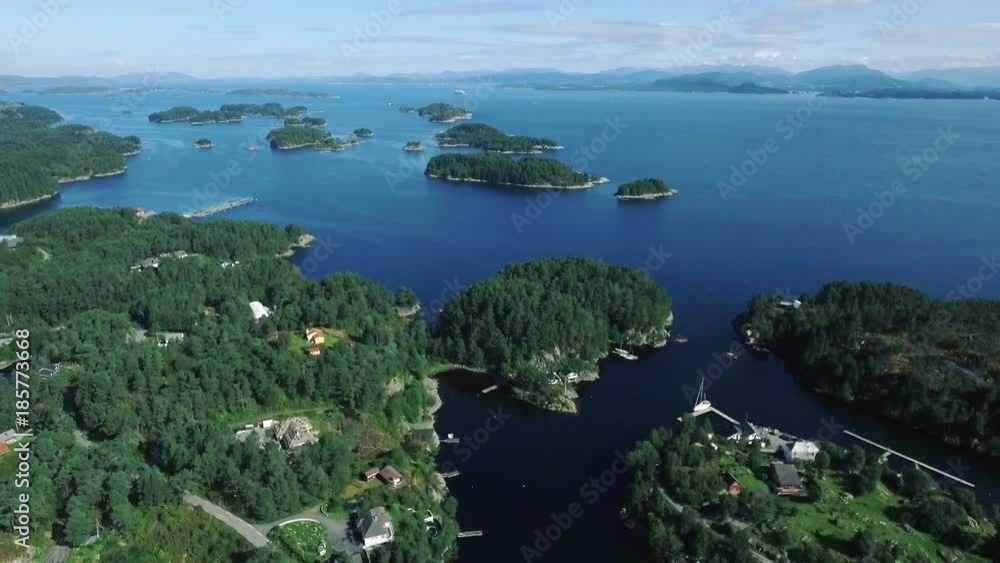 Slow flight beautiful islands of Norway in sunny weather, clear blue sea with reflecting sunlights on water. Thick green trees, pure water, village with beautiful sea harbor, mountains in background Slow flight beautiful islands of Norway in sunny weather, clear blue sea with reflecting sunlights on water. Thick green trees, pure water, village with beautiful sea harbor, mountains in background