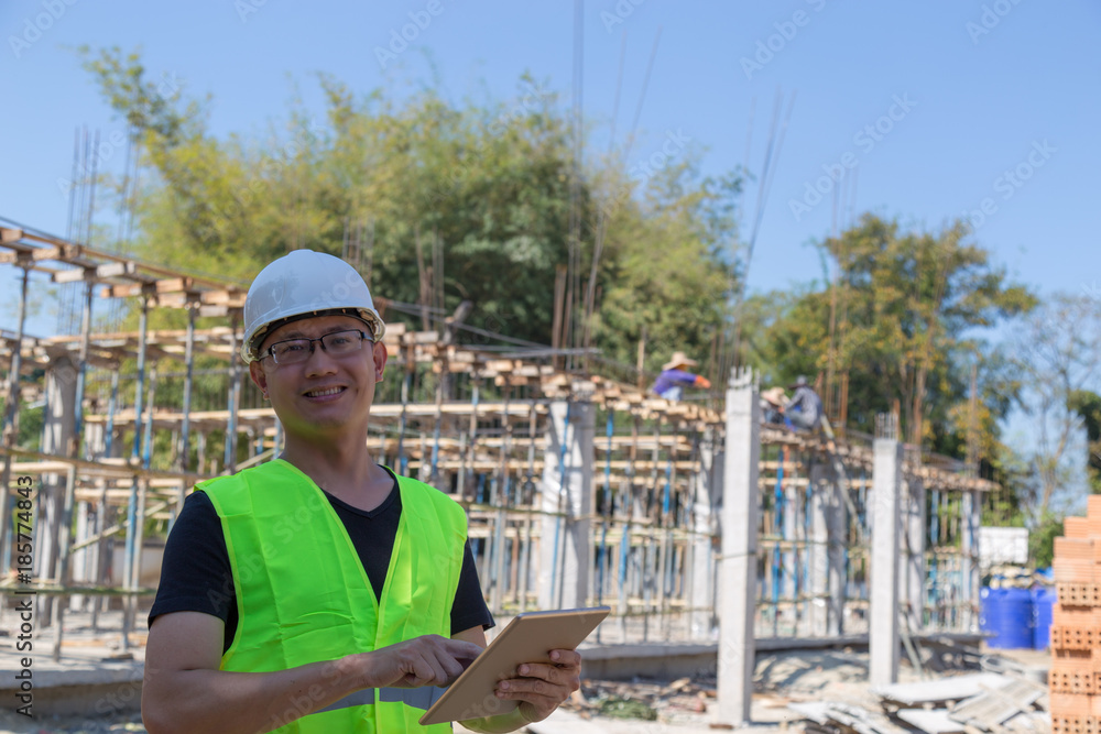Engineers wear a helmet and holding construction plan and tablet monitoring the construction area. Engineers wear a helmet and holding construction plan and tablet monitoring the construction area.