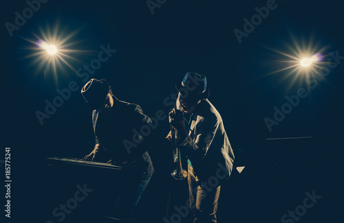 Musician Duo band playing a keyboard and singing on black background with spot light and lens flare, musical concept © THANANIT
