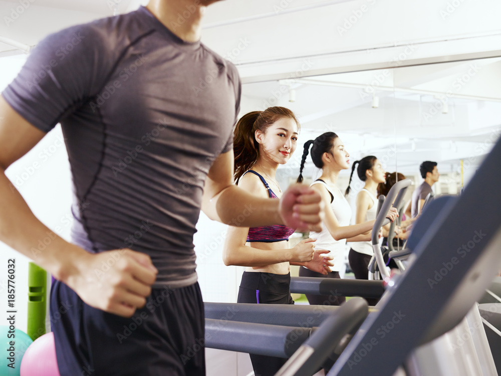 young asian people exercising on treadmill, focus on the girl in the middle young asian people exercising on treadmill, focus on the girl in the middle
