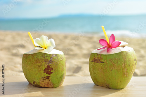 Coconut fruit with flower on wood table with blue sea and sky background