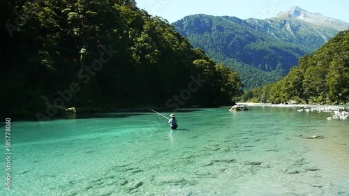 a female angler casts a fly rod on the beautiful wilkin river in new zealand's mt aspiring national park photo