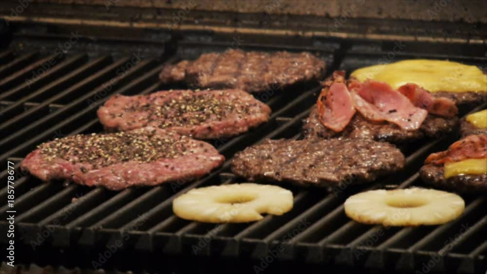 hamburger patties, pineapple and bacon cook on the grill of a restaurant hamburger patties, pineapple and bacon cook on the grill of a restaurant