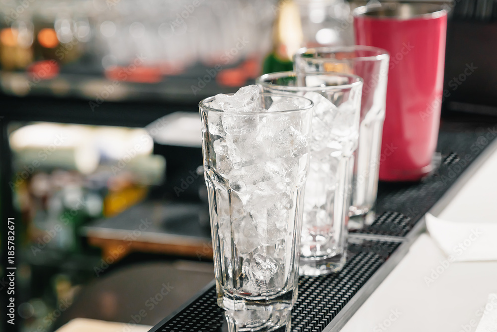 Empty, tall glasses of ice on the bar. Cocktail preparation, shaker. Empty, tall glasses of ice on the bar. Cocktail preparation, shaker.