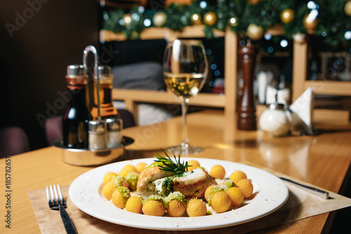 Chicken fillet with spinach and gnocchi on a white plate on a table in a restaurant. Table setting at the restaurant.