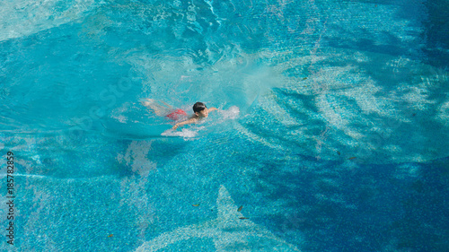 high angle view of Asian teenager swimming outdoors in blue pool