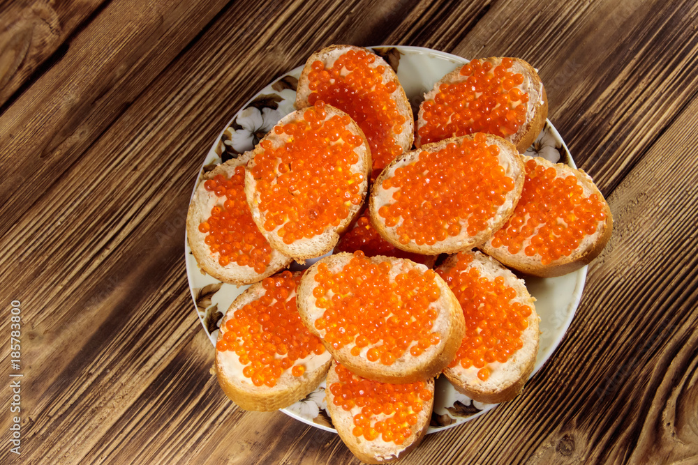Sandwiches with butter and red caviar on wooden table Sandwiches with butter and red caviar on wooden table