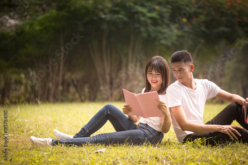 couple of high school students sit down and read a book in park, education concept