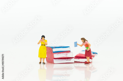 Miniature people: Women have read book already and keep book on shelf, using as education concept.